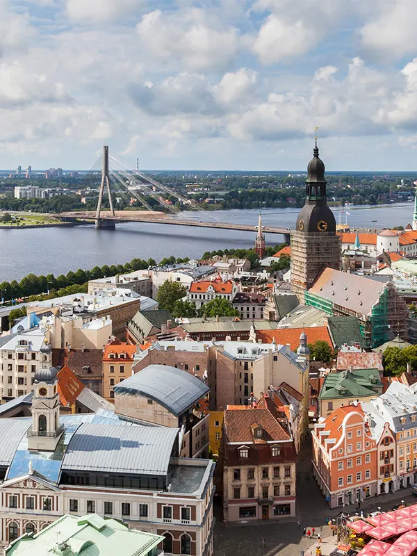 Aerial view of Riga old town rooftops with the Riga Cathedral tower, Vanšu suspension bridge and the Daugava river stretching into the horizon