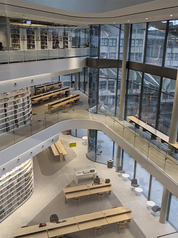 Open plan UTS library spanning multiple floors with curved glass balconies, rows of study desks and bookshelves overlooking the city