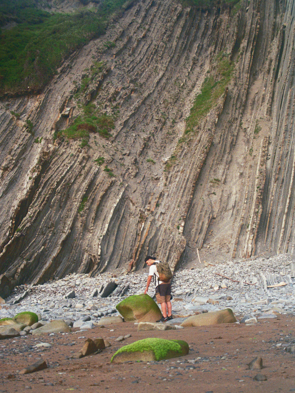 Student exploring rocky coastal cliffs in Bizkaia, Spain, surrounded by natural landscapes and geological formations