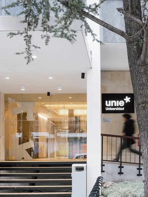 Entrance of UNIE Universidad in Madrid with modern glass facade and students passing by