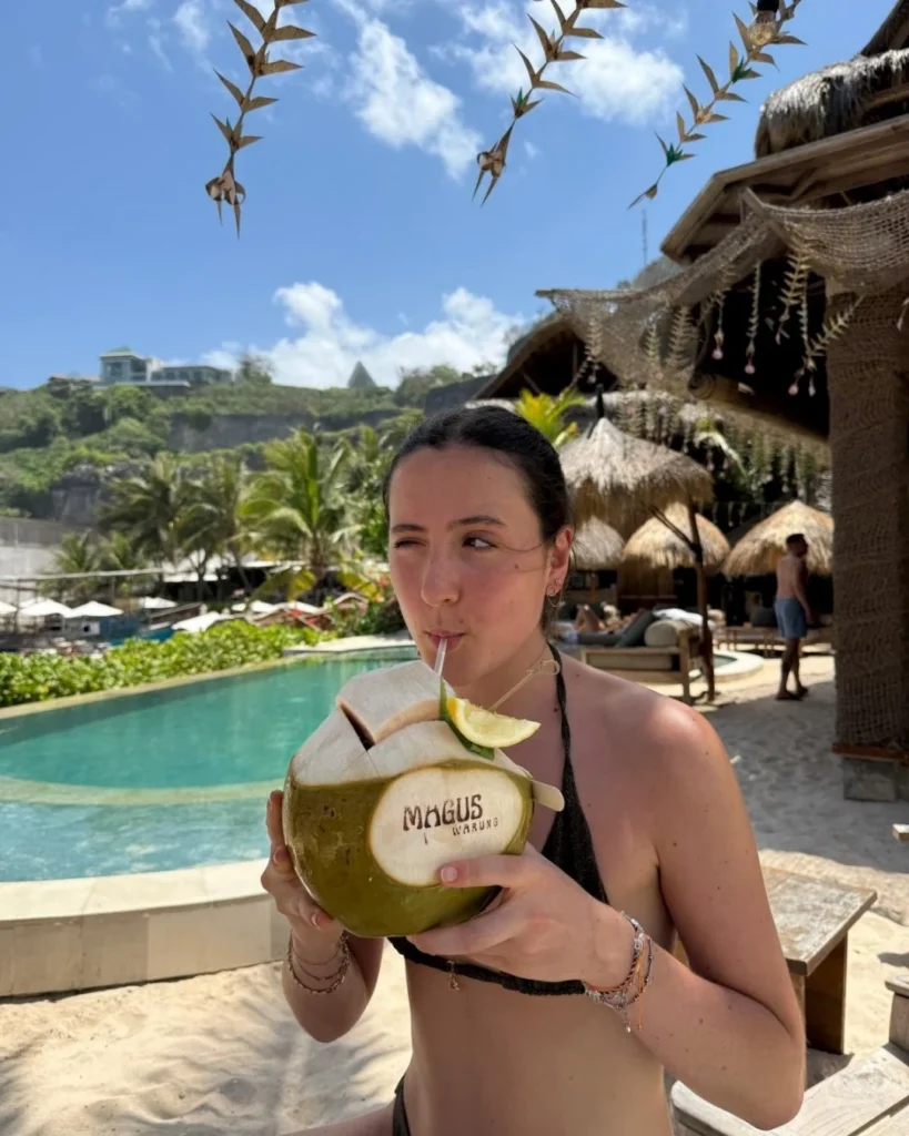 Emma, gap year student in Bali, drinking from a coconut at the beach